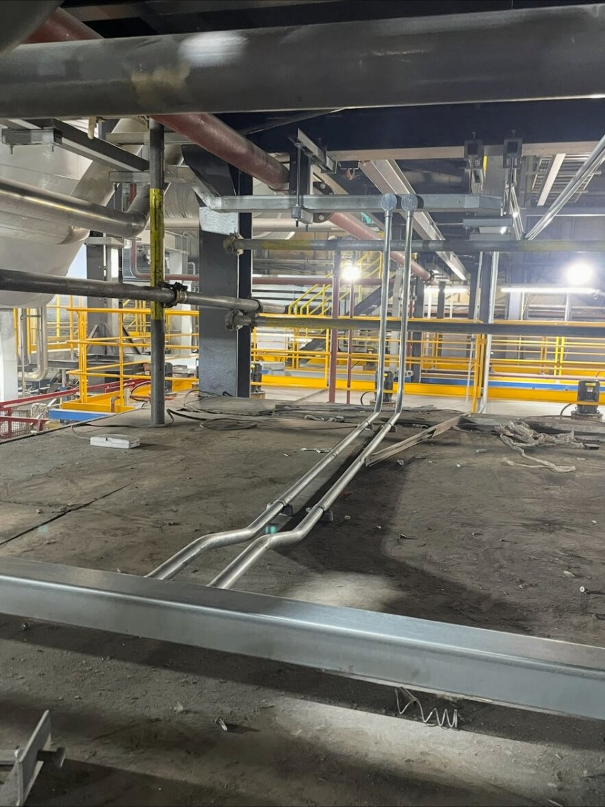 Galvanised conduit drops to floor-mounted plant and instrumentation on an industrial process site.