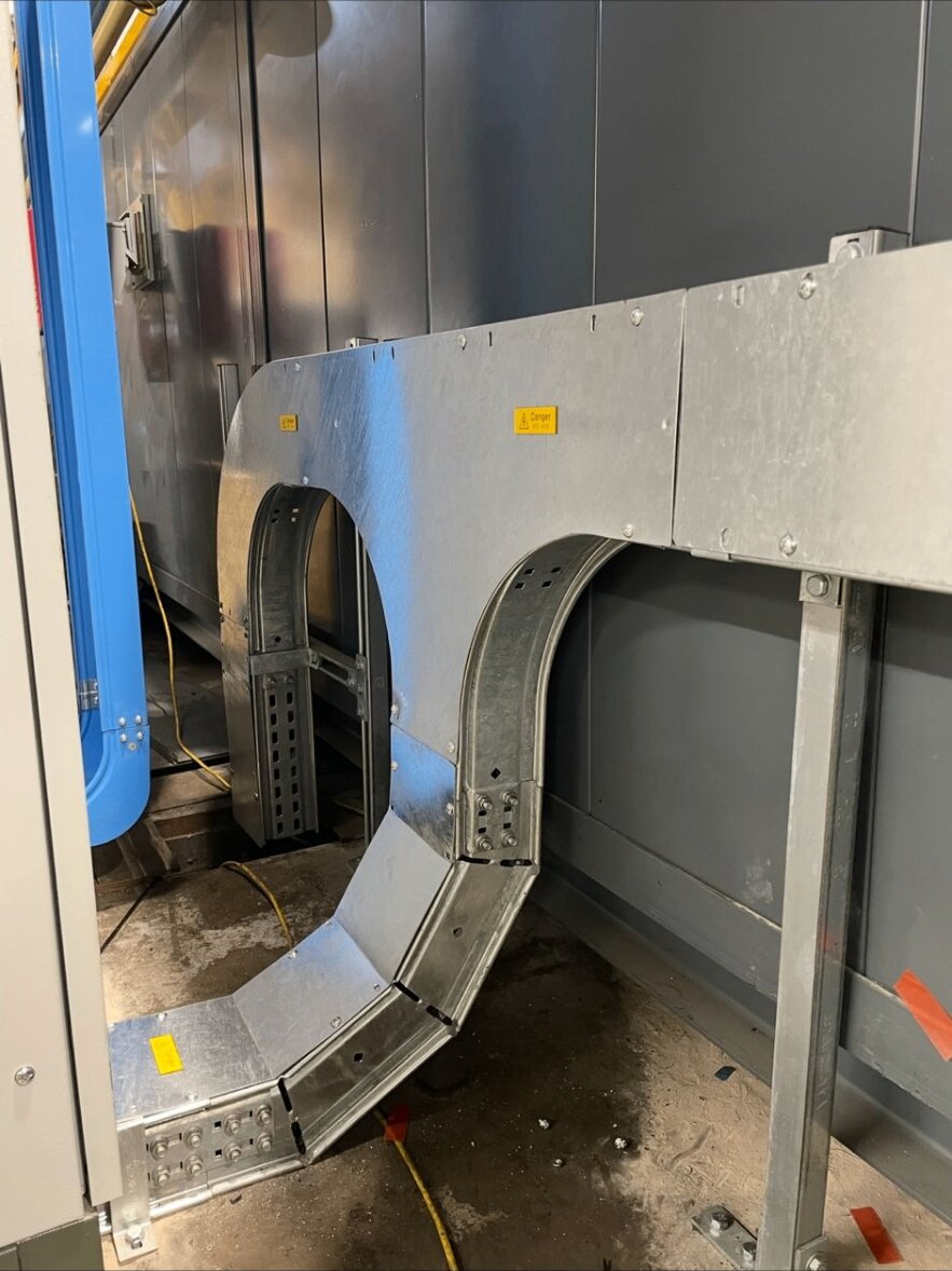 Heavy-duty galvanised cable tray bend leaving a process panel at a Nottinghamshire industrial site